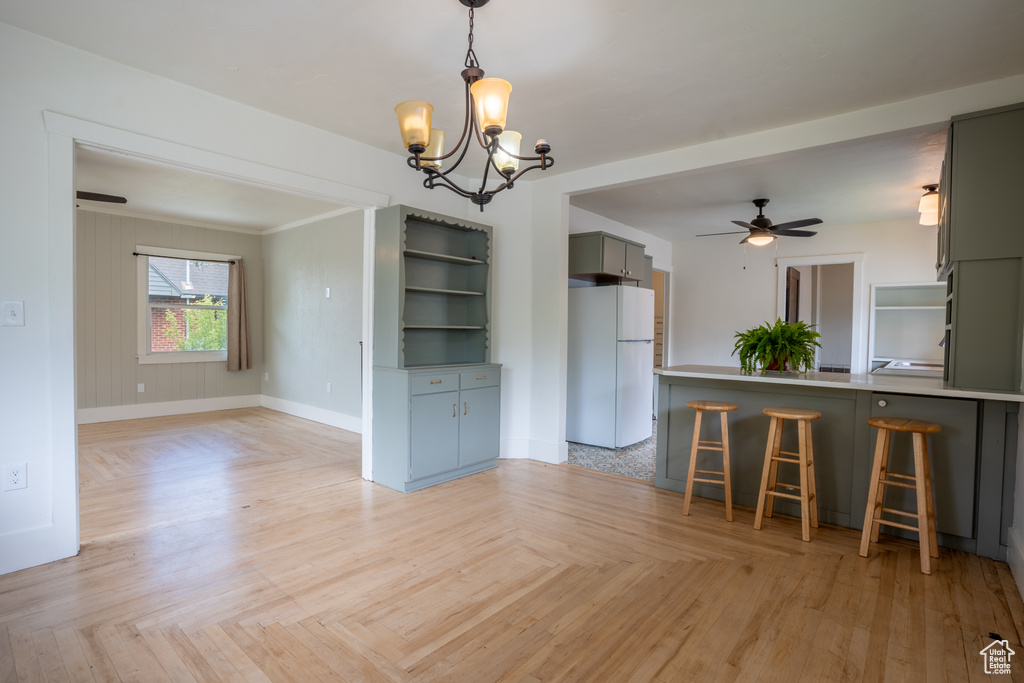 Unfurnished dining area with a chandelier, a ceiling fan, and baseboards