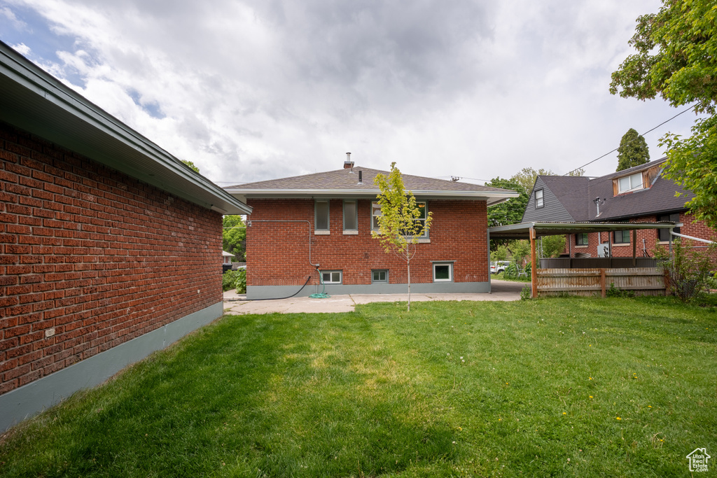 Rear view of property with a patio area, brick siding, and a lawn
