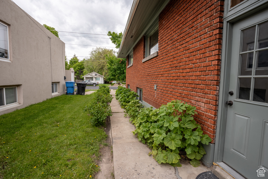 View of side of home featuring brick siding and a yard
