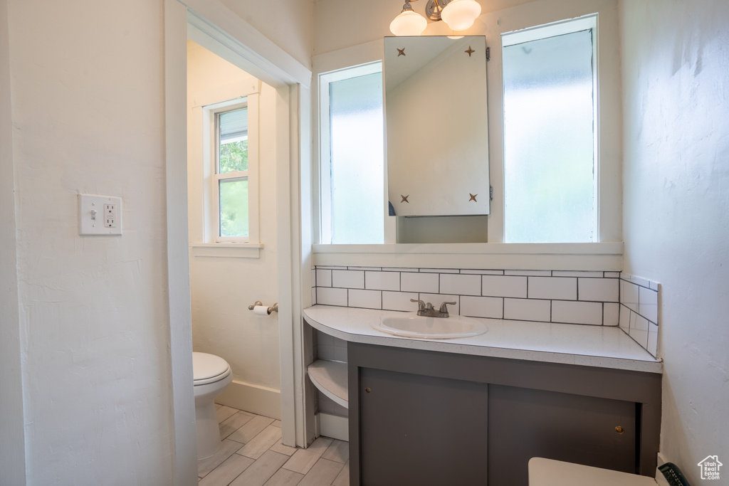Bathroom featuring toilet, vanity, and backsplash