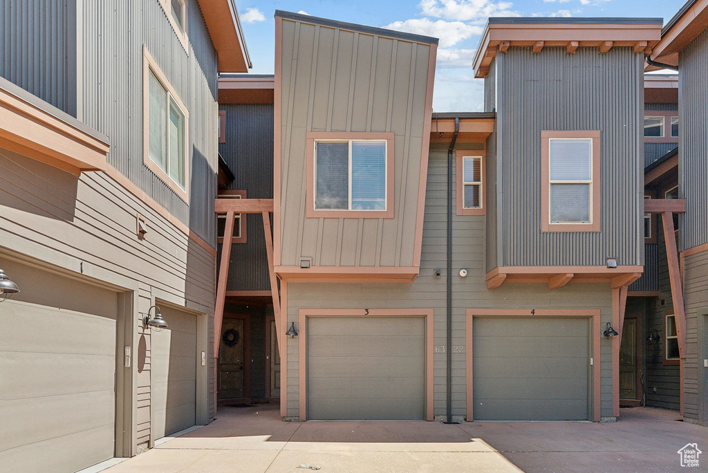 View of front facade with driveway, an attached garage, and board and batten siding