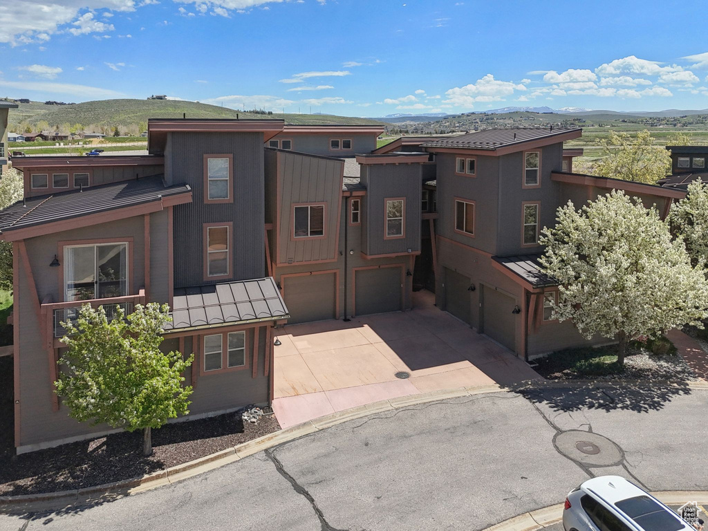 View of front of house featuring a mountain view, a standing seam roof, an attached garage, metal roof, and driveway