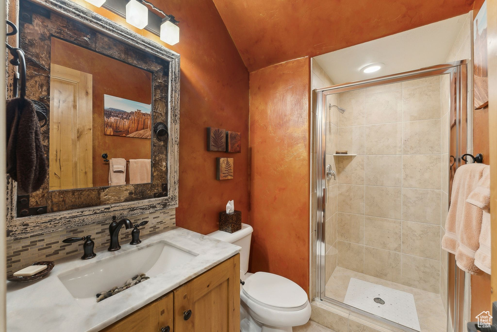 Full bathroom featuring toilet, vanity, a shower stall, and vaulted ceiling