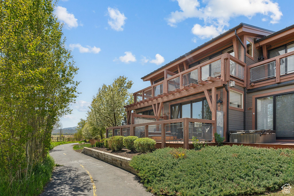 Back of house with a hot tub and a balcony