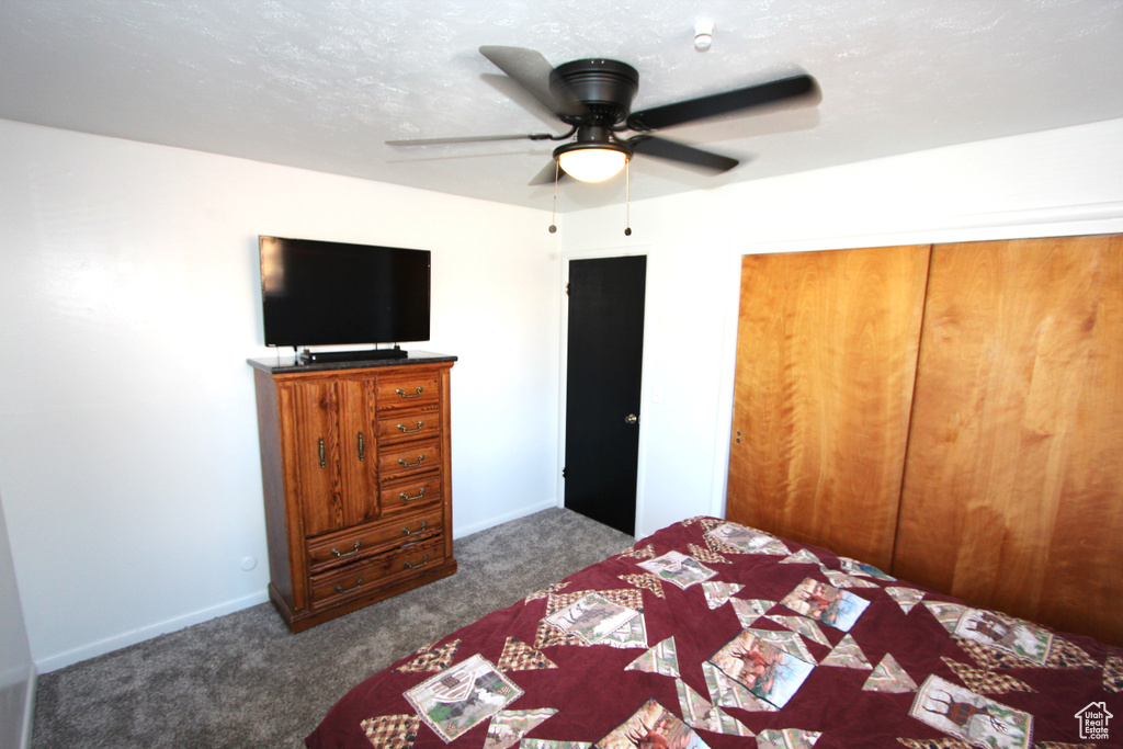 Bedroom with dark carpet, ceiling fan, a closet, and baseboards