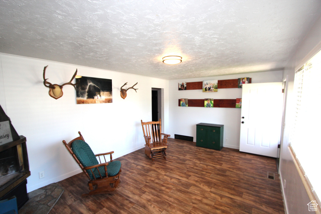 Unfurnished room featuring wood finished floors, a textured ceiling, baseboards, and a wood stove