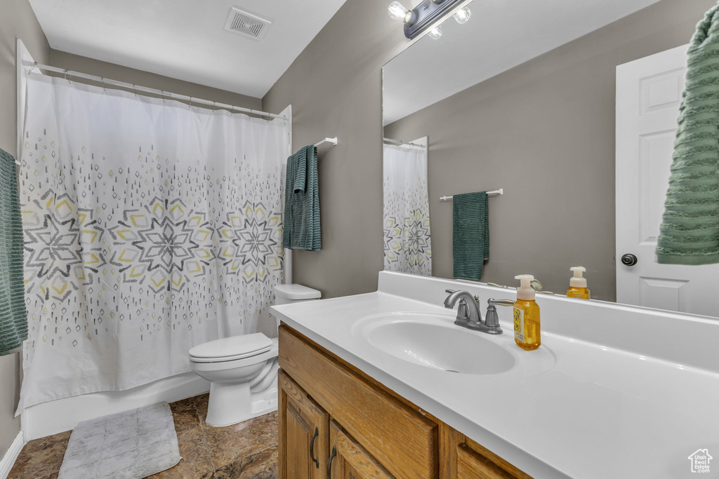 Full bathroom featuring toilet, vanity, and stone finish flooring