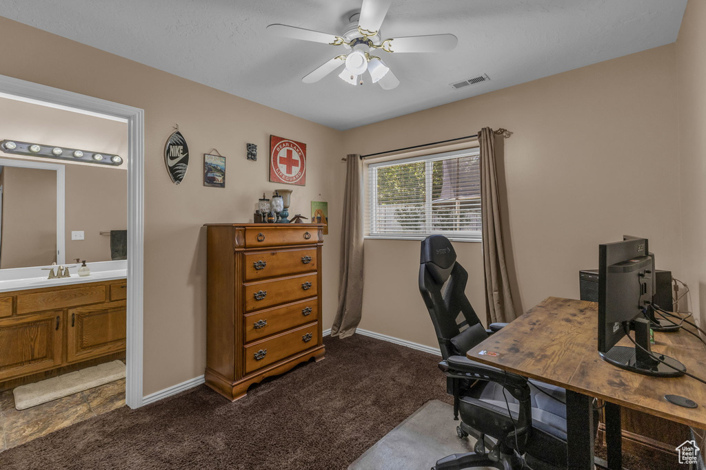 Office area with a ceiling fan, dark carpet, baseboards, and a sink