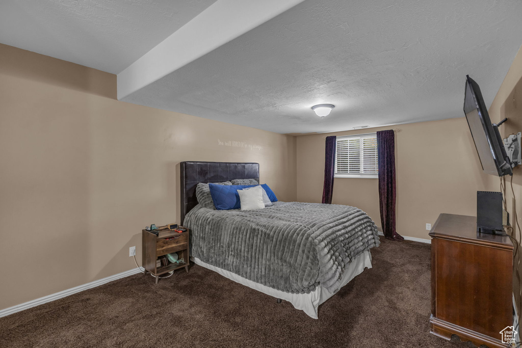 Carpeted bedroom featuring baseboards and a textured ceiling