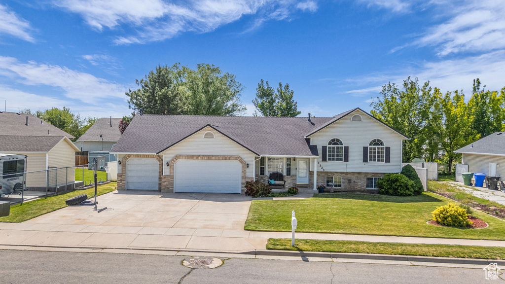 Split level home with a garage, concrete driveway, and a shingled roof