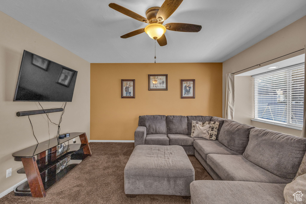Carpeted living room with ceiling fan and baseboards