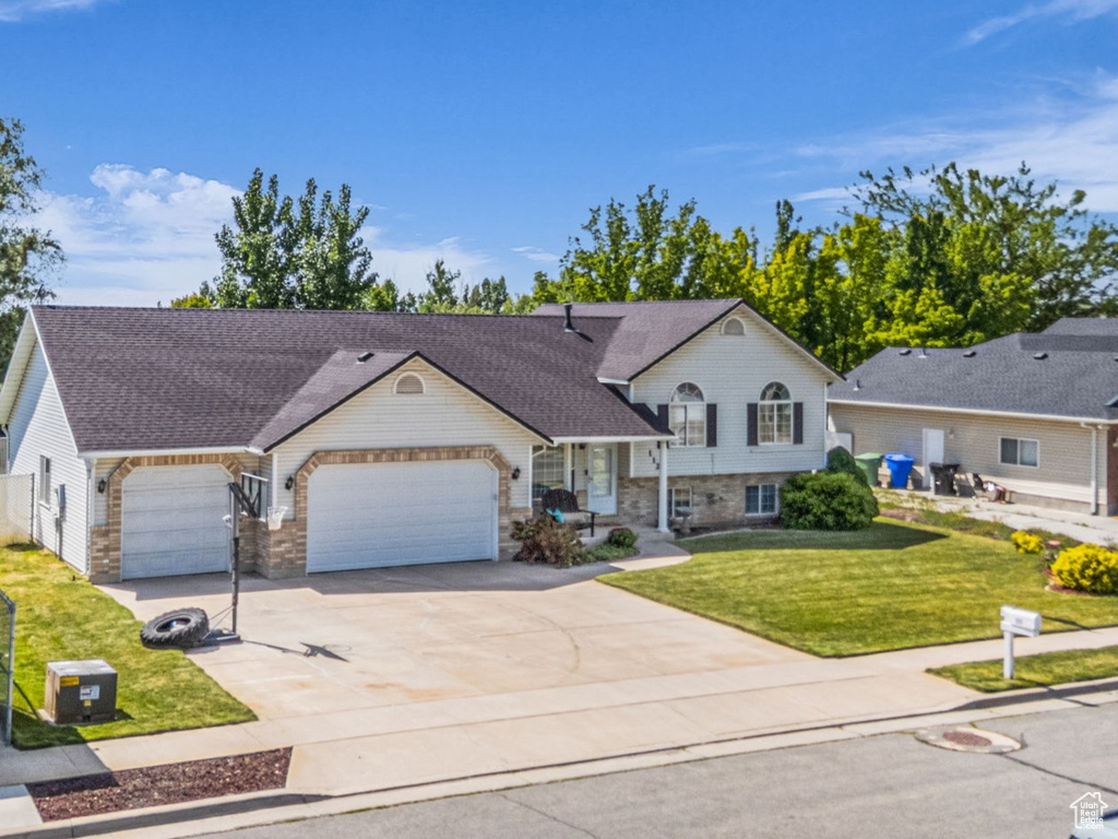 View of front of house with an attached garage, driveway, a front yard, and stone siding