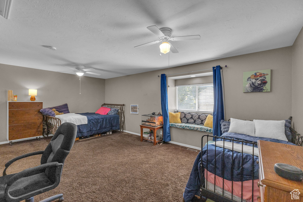 Carpeted bedroom featuring baseboards, a ceiling fan, and a textured ceiling