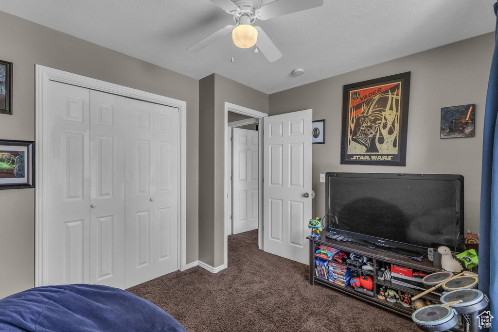 Playroom with dark carpet, ceiling fan, and baseboards