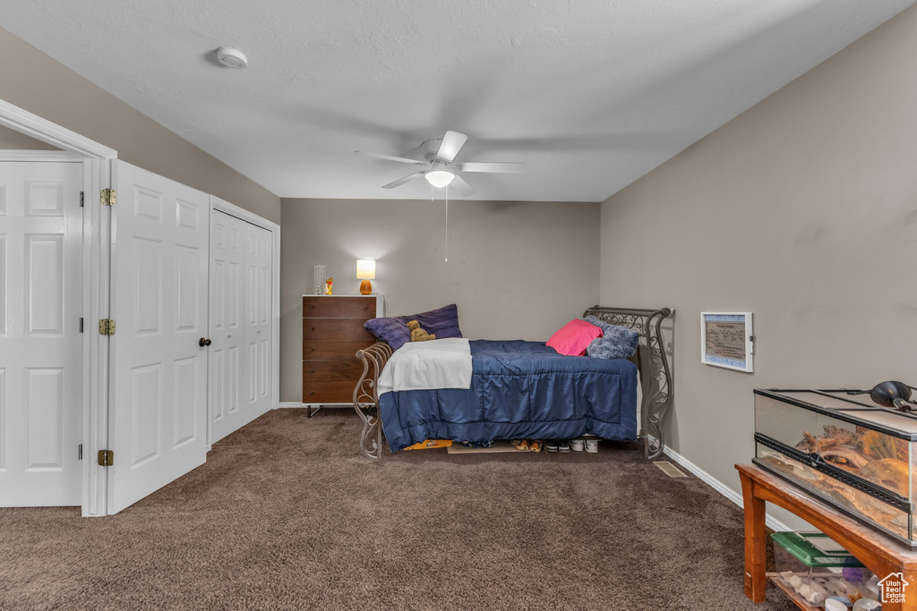 Carpeted bedroom with ceiling fan and baseboards