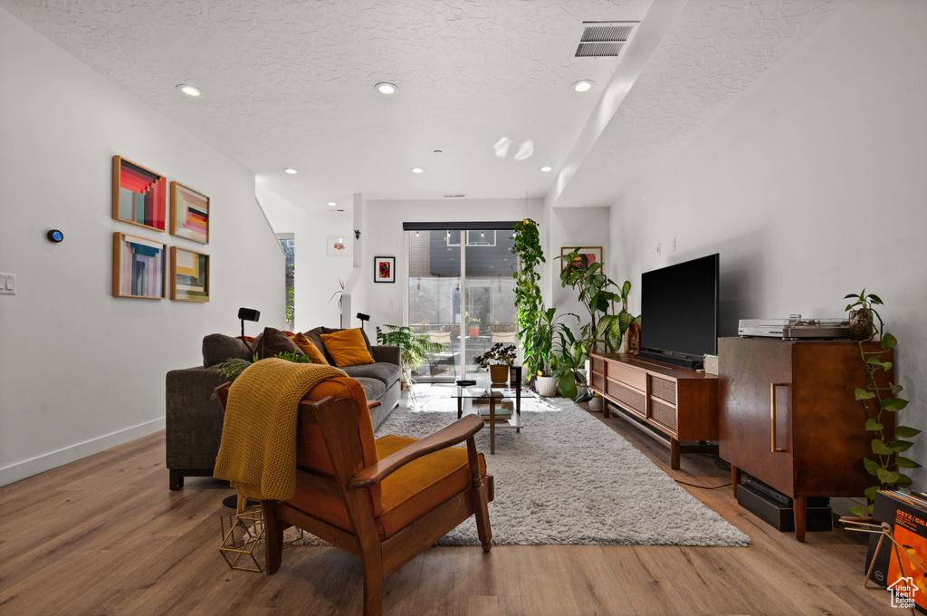 Living area featuring a textured ceiling, light wood-type flooring, recessed lighting, and baseboards