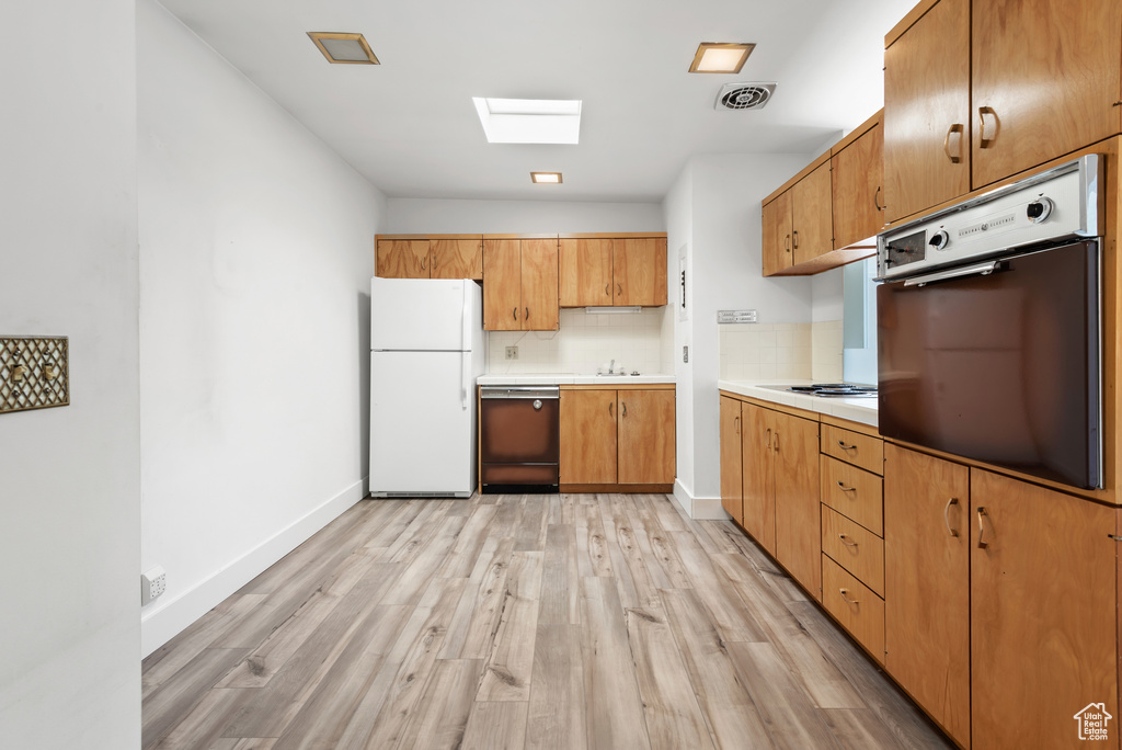 Kitchen featuring white appliances, light wood-style floors, baseboards, and light countertops