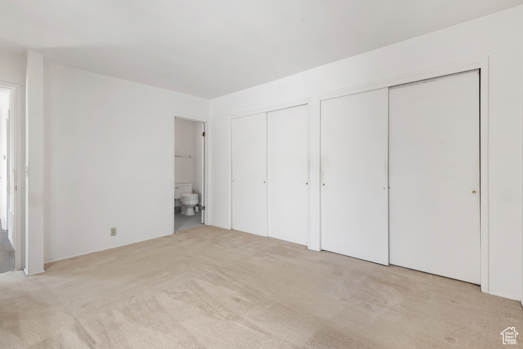 Unfurnished bedroom with multiple closets, carpet flooring, and ensuite bathroom