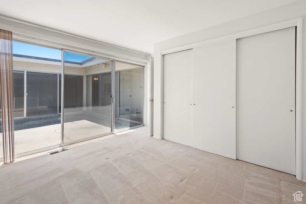 Unfurnished bedroom with carpet flooring, access to exterior, and a closet