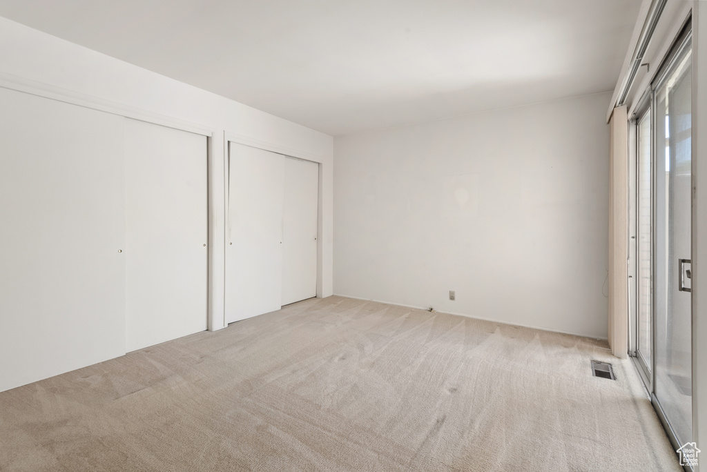 Unfurnished bedroom with multiple closets and light carpet