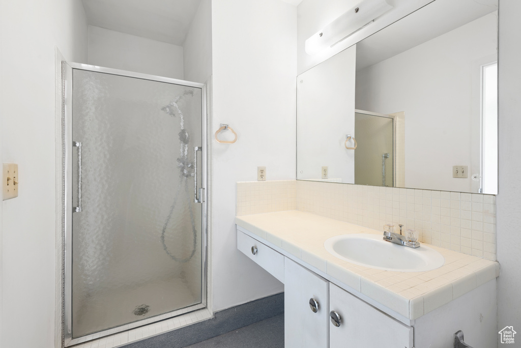 Bathroom featuring backsplash, vanity, and a shower stall