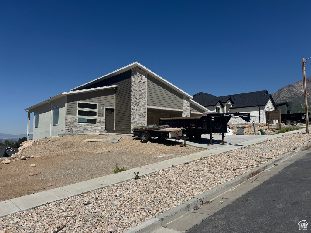 View of property exterior featuring stone siding, a mountain view, and mail area