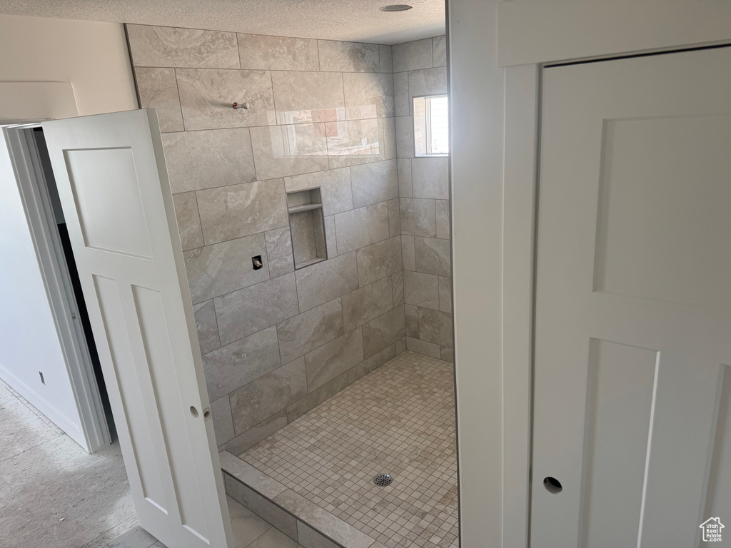 Full bathroom featuring tiled shower and a textured ceiling