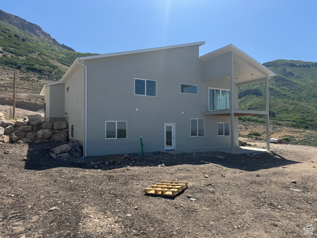 Back of house featuring a mountain view, stucco siding, and a balcony