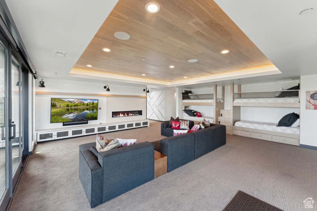 Carpeted living room with a raised ceiling, wood ceiling, and recessed lighting