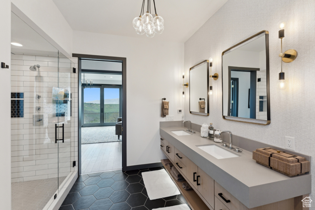 Bathroom featuring double vanity, a shower stall, baseboards, tile patterned flooring, and a chandelier