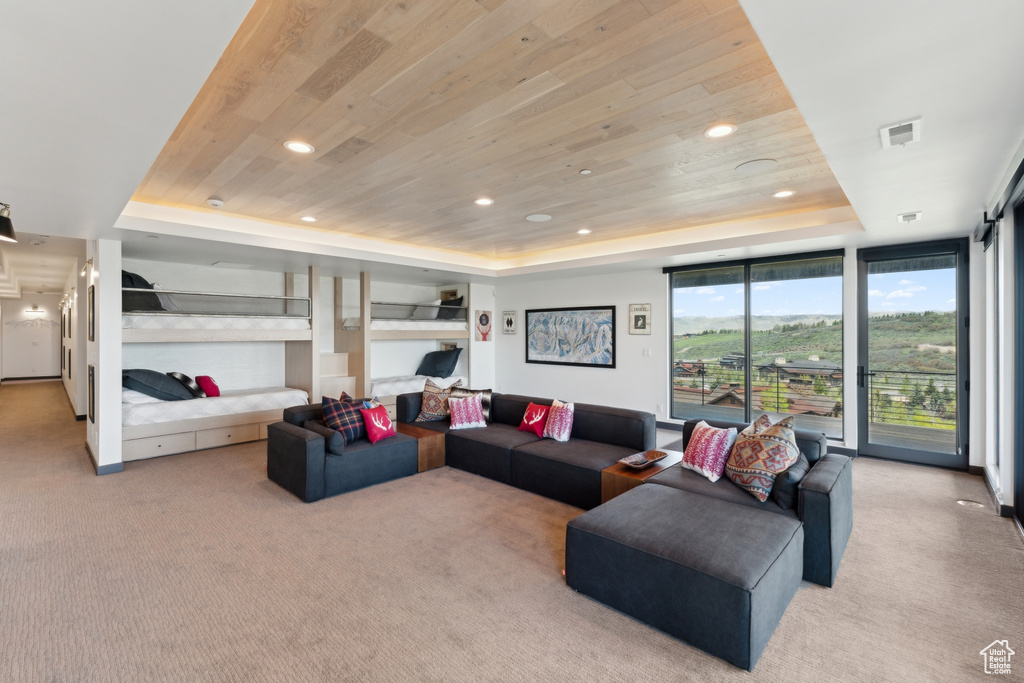 Living area with a tray ceiling, wood ceiling, light carpet, recessed lighting, and floor to ceiling windows