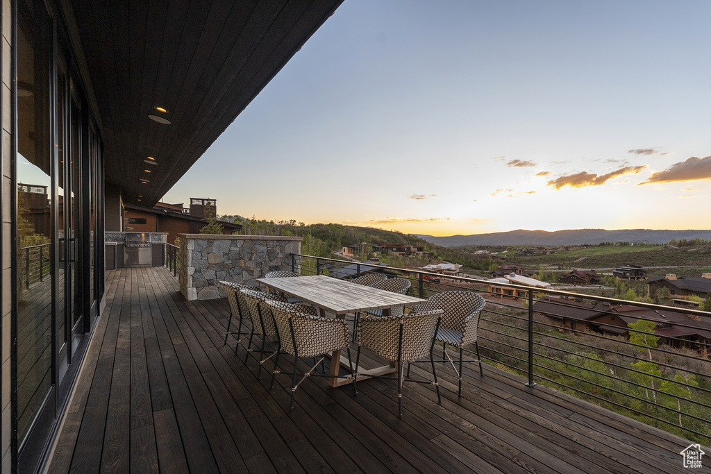 Deck at dusk with a mountain view and exterior kitchen