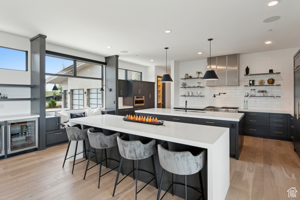 Kitchen with open shelves, a spacious island, light countertops, light wood-style flooring, and recessed lighting