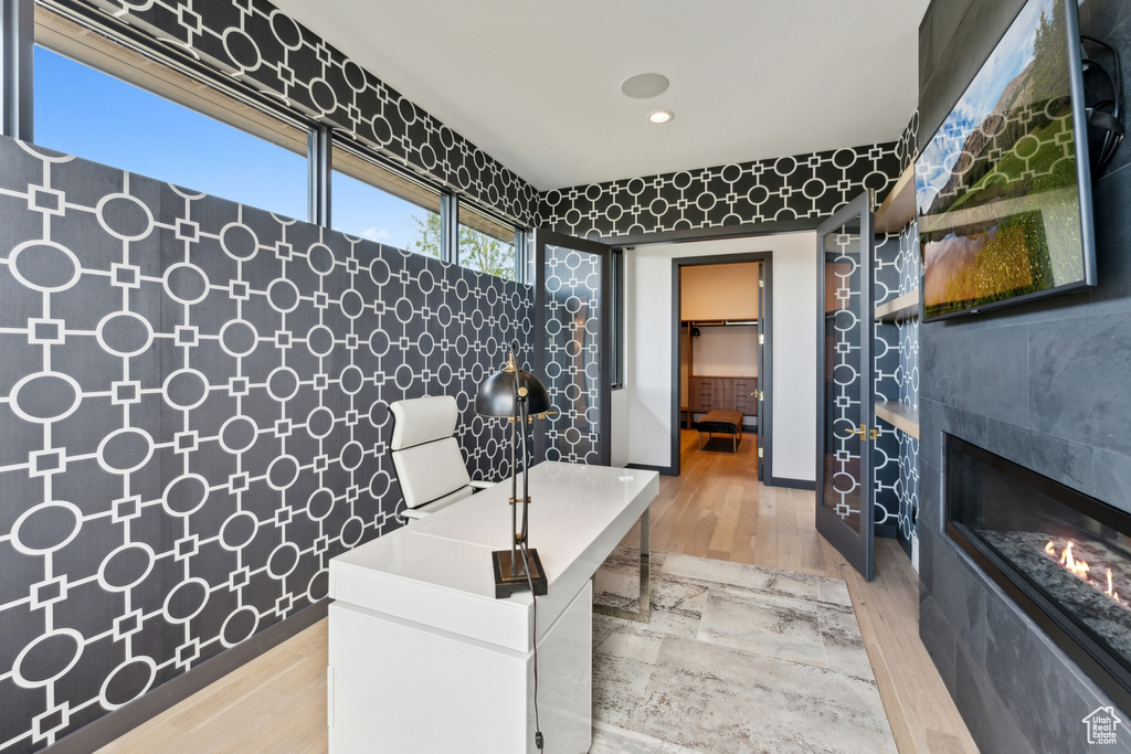 Home office with light wood-style floors, a glass covered fireplace, and recessed lighting