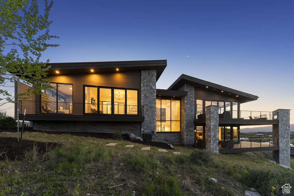 Back of property featuring stone siding and a balcony