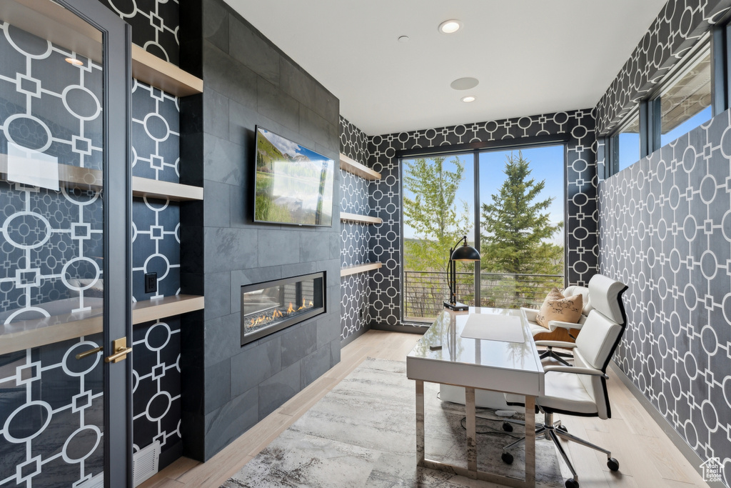 Office area featuring light wood-type flooring, a tile fireplace, wallpapered walls, and recessed lighting