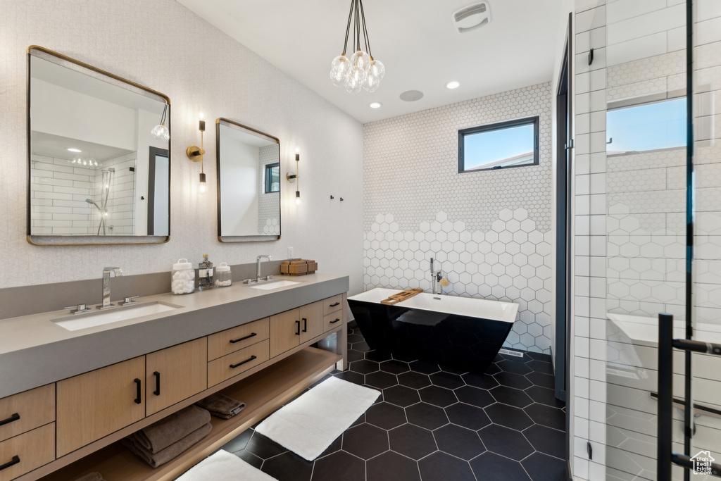 Full bath featuring double vanity, tile patterned flooring, a freestanding bath, a chandelier, and recessed lighting