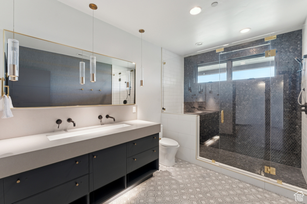 Bathroom featuring toilet, vanity, a stall shower, and tile patterned flooring