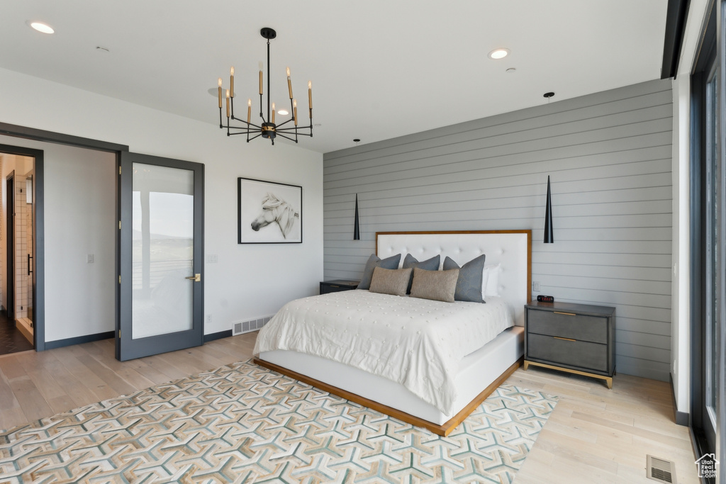 Bedroom with light wood-type flooring, a chandelier, wooden walls, recessed lighting, and baseboards