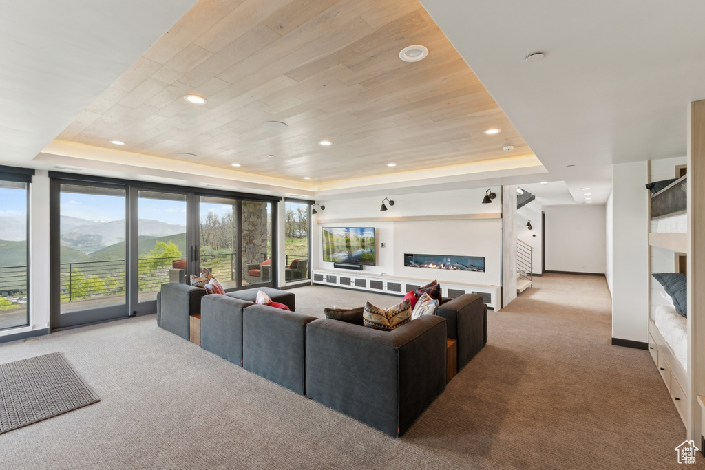 Carpeted living area featuring a tray ceiling, recessed lighting, baseboards, and wood ceiling