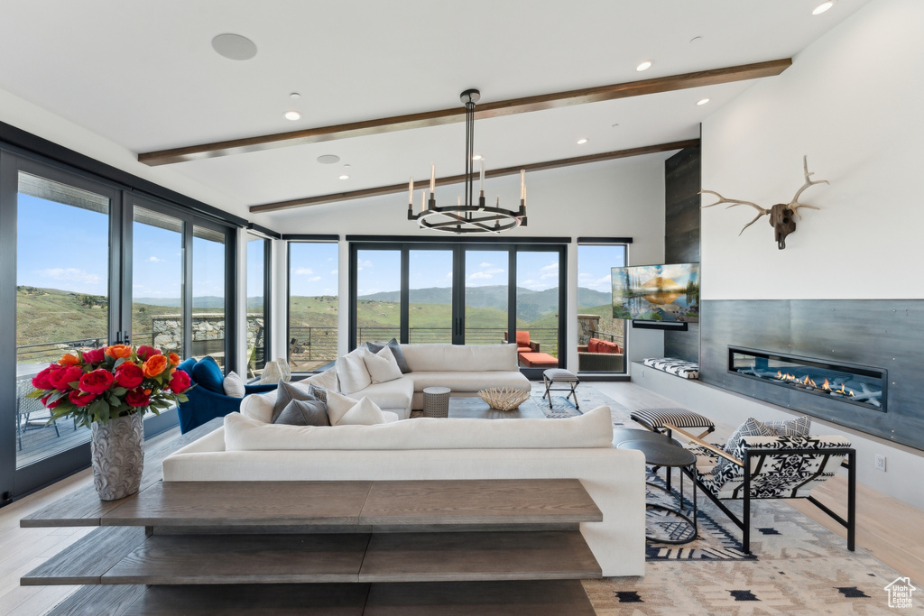 Living room featuring a glass covered fireplace, a chandelier, wood finished floors, and recessed lighting
