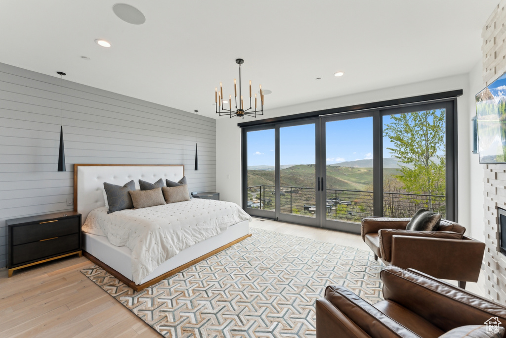 Bedroom with access to outside, a chandelier, light wood finished floors, recessed lighting, and wooden walls