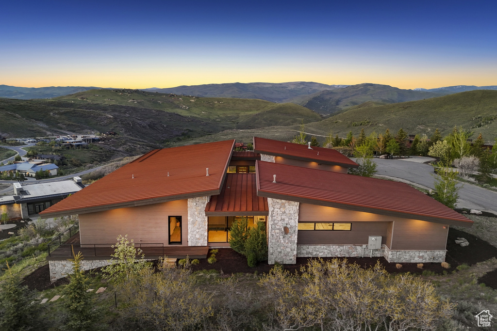 View of front facade featuring a mountain view, stone siding, and a garage