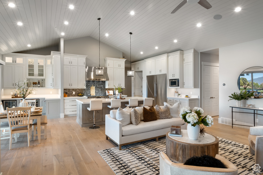 Living room with vaulted ceiling, light wood-style flooring, a ceiling fan, recessed lighting, and wooden ceiling