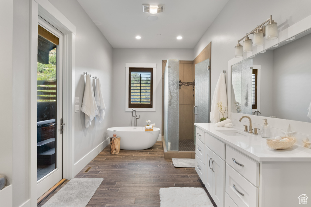Bathroom with vanity, a shower stall, a freestanding tub, wood finished floors, and recessed lighting
