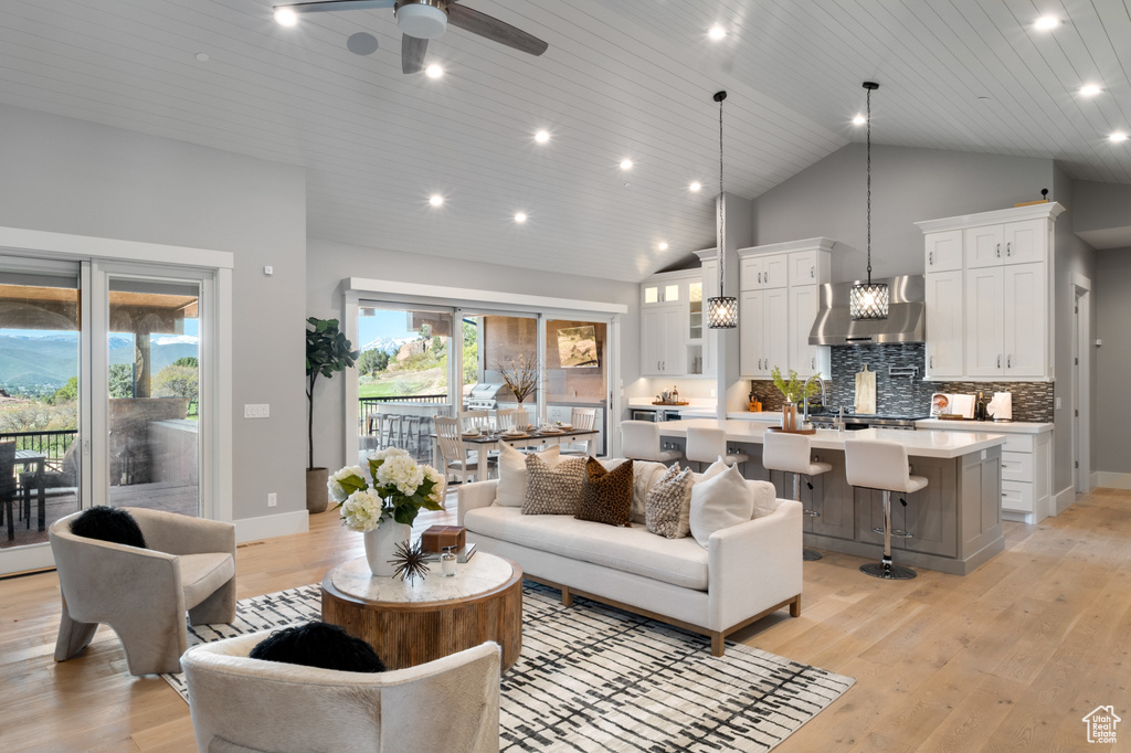 Living area with light wood-style flooring, ceiling fan, recessed lighting, high vaulted ceiling, and a chandelier