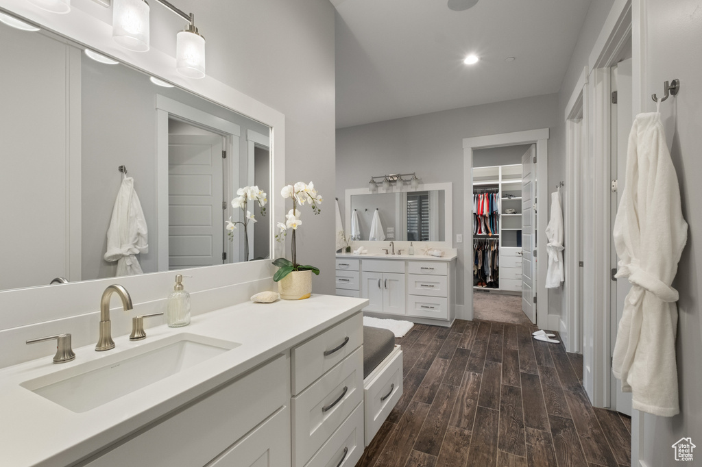Bathroom with vanity, wood finished floors, and a spacious closet