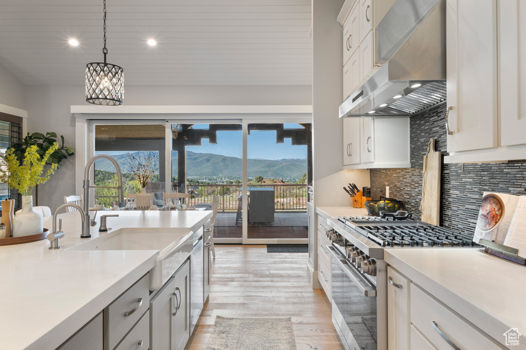 Kitchen featuring wall chimney range hood, stainless steel appliances, a mountain view, healthy amount of natural light, and recessed lighting