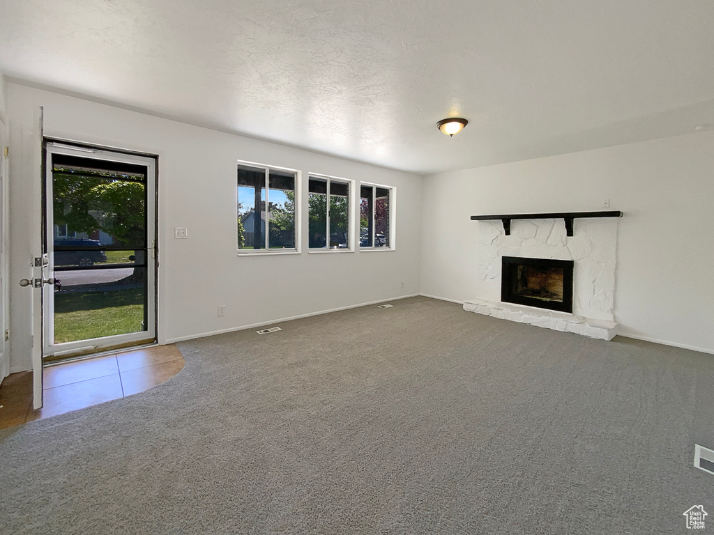 Unfurnished living room with healthy amount of natural light, a fireplace, carpet floors, and baseboards
