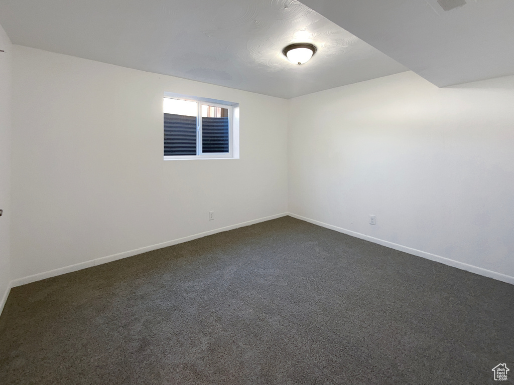 Empty room with baseboards and dark colored carpet